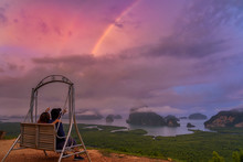 Scene Of Lovers Sitting And Pointing To The Rainbow Over The Fantastic Landscape Of Samed Nang Chee View Point At The Sunrise Time, Travel And Holiday Concept