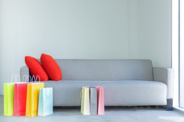 Shopping online. Colorful shopping bags with red pillow on sofa in the living room.