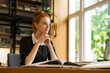 Smiling red haired teenage girl studying at the table