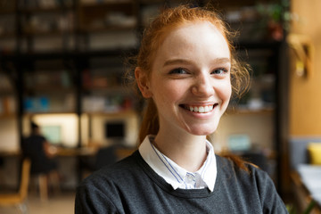 Canvas Print - Happy redhead lady student posing indoors in library.