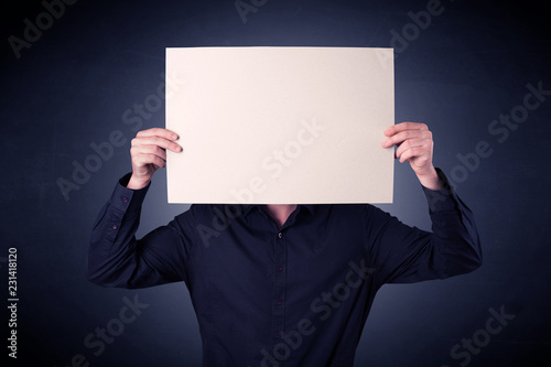 Fotografie, Obraz Young businessman hiding behind a blank piece of paper