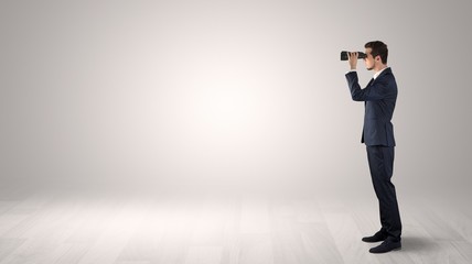 Wall Mural - businessman looking forward with binoculars in an empty space