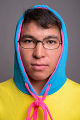 Young Asian man wearing colorful hoodie and eyeglasses against g