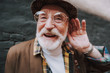 © Yakobchuk Olena - Concept of positive mood lifestyle of hearing impaired person. Close up portrait of happy pensioner with playful glance holding palm near his ear