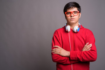 Wall Mural - Young Asian teenage boy wearing headphones against gray backgrou