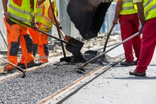 Workers Construct Asphalt Road And Railroad Lines