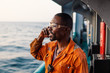 © Igor Kardasov - Marine Deck Officer or seaman on deck of vessel or ship . He is speaking on the mobile cell phone