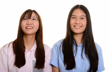 Two young happy Asian teenage girls smiling and thinking 