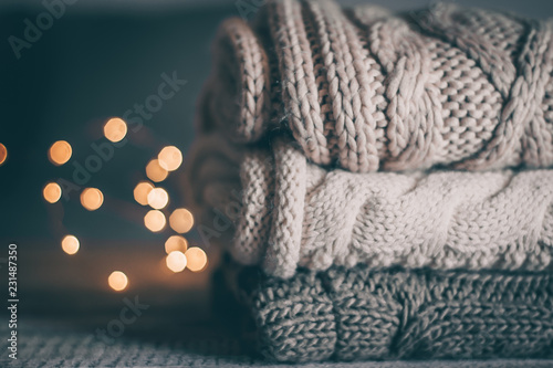 Fotografía Stack of cozy knitted sweaters and garland lights on wooden background