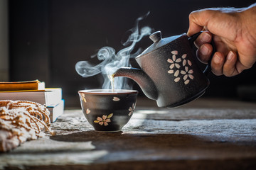 Wall Mural - Still life details Pouring tea in teapot and cup with steam on wood background. Winter tea time.