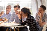 Fototapeta  - Indian woman laughing at funny joke eating pizza with diverse coworkers in office, friendly work team enjoying positive emotions and lunch together, happy colleagues staff group having fun at break