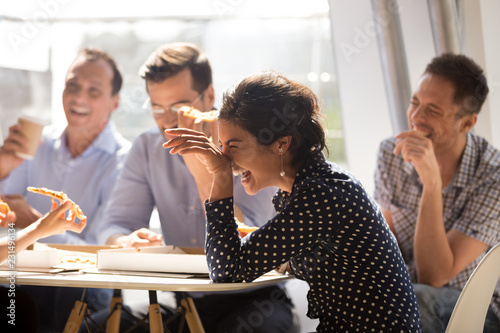 Cuadros en Lienzo Indian woman laughing at funny joke eating pizza with diverse coworkers in offic