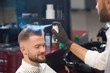 © serhiibobyk - Barber fixating hair of male with spray in barber shop