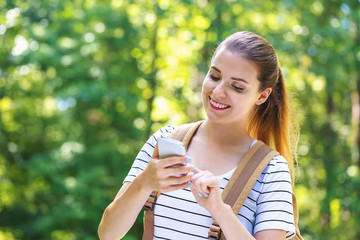 Wall Mural - Young woman using her smartphone on a bright summer day in the forest