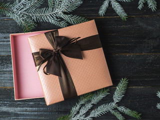 Beautiful open gift box with bow. Lying on a dark wooden table with branches of a Christmas tree in the snow . A gift for the new year