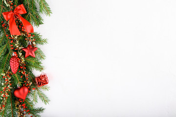 Spruce branches decorated with red ornaments and red barberry berries on a white background.