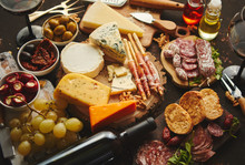 Huge Assortment Of Various Tasety Spanish, French Or Italian Apertizers. Cheese, Meat, Olives, Stuffed Peppers, Bread, Sticks. Placed On Rusty Dark Background. View From Above.