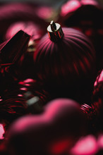 Close Up Of Dark Red Christmas Decoration Ornaments, Balls, Baubles, Stars, Swirls And Heart Shaped With Golden Details And Bokeh Blur In Background For Festive Holiday Or Seasons Greetings Card
