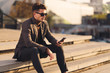 © Goran - Young businessman using cell phone while relaxing on staircase outdoors.
