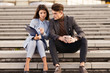 © Goran - Two serious business people having a coffee break. They are sitting on a staircase and reading something from clipboard together.