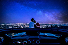 Couple Watching Sunset From Popular View Point In Los Angeles, California. Sitting On The Sport Convertible Car Hood
