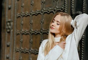 Closeup portrait of sensual girl with natural makeup posing near metal wrought door. Space for text