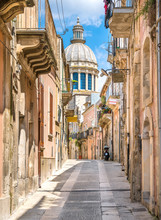 A Narrow And Picturesque Road In Ragusa Ibla With The Dome Of Saint George Duomo. Sicily, Southern Italy.