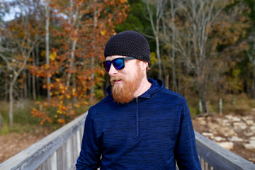 Redheaded man standing on bridge over lake