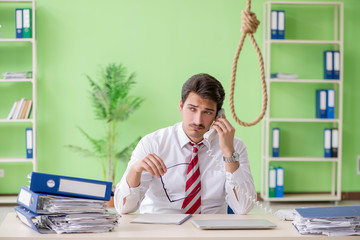 Despaired businessman thinking of suicide in the office 