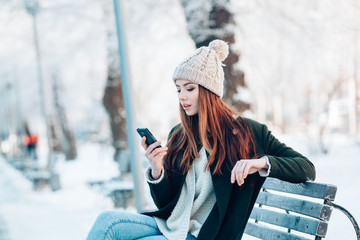 Young  woman smiling with smart phone and winter landscape .