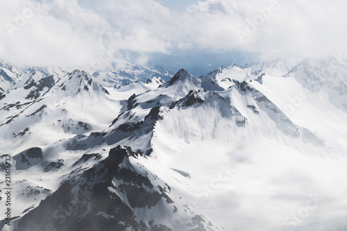 Fotomural Panoramic view of high mountain peaks in snowy and foggy cold weather