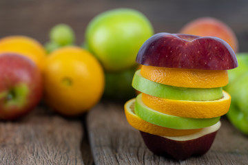 Orange, red apples, green apples Cut into pieces on wooden floor