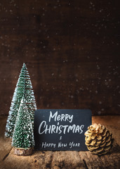 Aufkleber - Merry Christmas and happy new year on blackboard with xmas tree and gold pine cone and snow falling on grunge wood table and dark brown wooden wall.winter holiday greeting card.