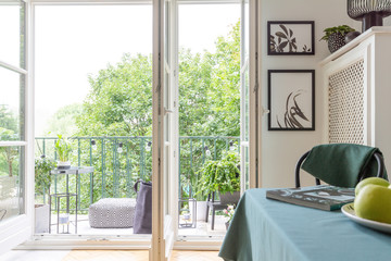 Open door, balcony and posters on the wall in stylish apartment, real photo