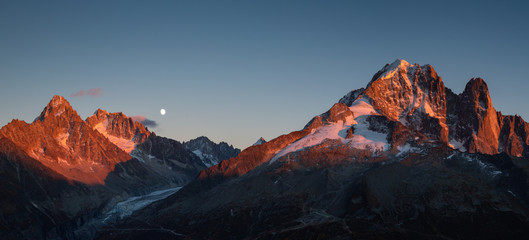 Fototapete - Panorama of the last sunlight on the mountain peaks near Chamonix, France, during moonrise.