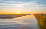 Fototapeta Krajobraz - Shore of a canal in the countryside at sunrise in autumn