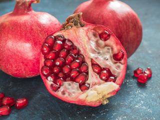 Fresh ripe red pomegranate fruit on a dark blue rustic background. Healthy food, closeup, flat lay, top view