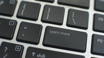 Learn more button on computer keyboard, female hand fingers press key
