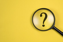 Magnifying Glass With QUESTION MARK In Focus On Yellow Background. Concept Of Search And Research.
