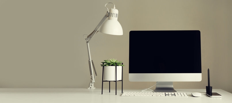 Designer workspace. Banner. Minimalistic home office. Blank screen desktop computer. Mockup desktop computer, lamp, graphics tablet, keyboard, mouse, pen, succulent plant on white desk. Copy space