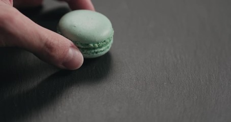 Wall Mural - Slow motion closeup man hand put light blue macaron on slate board