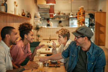 Wall Mural - Diverse friends talking over food and drinks in a bistro