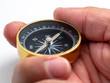 © Prot - closeup man hand holding golden compass on white background (Isolated background)