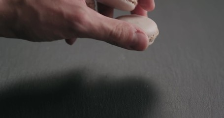 Wall Mural - Slow motion closeup man hand put beige macarons on slate board