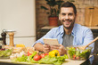 © denis_vermenko - Man preparing delicious and healthy food in the home kitchen on a sunny day. Using tablet computer for searching recipes.