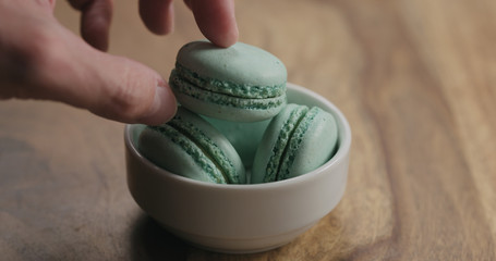 Wall Mural - man hand put light blue macarons in white bowl on wood table