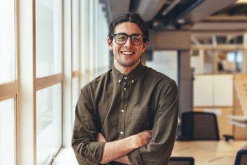 Happy businessman standing in office