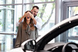 © Kalim - Adult man making surprise to beautiful woman in car showroom