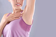 Young woman with sweat stain on her clothes against grey background, space for text. Using deodorant