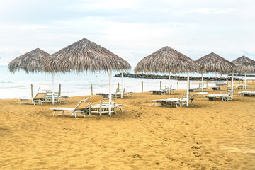 set for rest on a beach deck chair and umbrella, covered with dry grass or straw, empty beach at the resort in the early morning